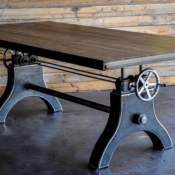 Een Hure Crank tafel ontwerp met een industrieel onderstel van zwart ijzer en houten tafelblad.